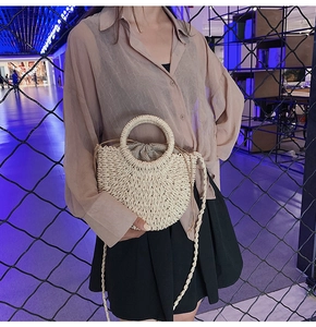 Detail shot of summer straw woven handbag with round handle, polka dot lining and shoulder strap.