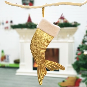 Close-up of golden sequined mermaid tail Christmas stocking with beige plush trim on branch