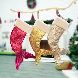Three mermaid tail Christmas stockings in pink, gold, and silver on a festive mantel