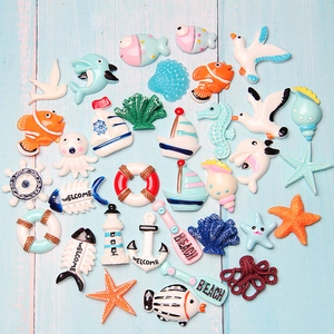 Assorted nautical resin charms with sea shells and anchors on light blue wood background
