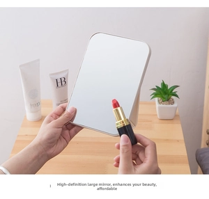 Close-up of a portable folding makeup mirror used with lipstick on a wooden desk