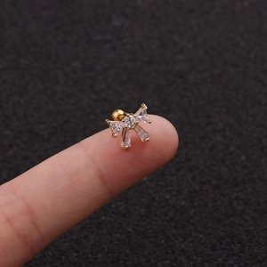 Macro view of a gold-plated bow earring with cubic zirconia held on a fingertip