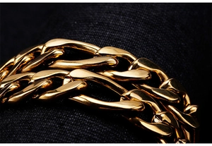 Macro detail of thick gold-plated stainless steel link chain on dark textured background