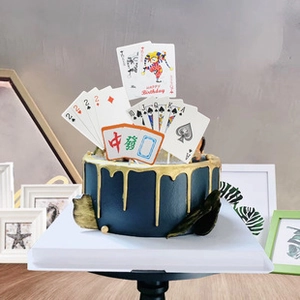 Detail showing poker cards and mahjong tiles cake topper on a blue birthday cake
