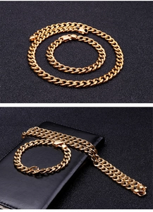 Close-up of golden Cuban link necklace and bracelet set displayed on a leather wallet