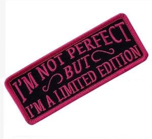 Close-up of embroidered tactical patch featuring pink letters on black background