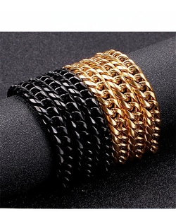 Close-up of gold and black stainless steel Cuban link bracelets on a display