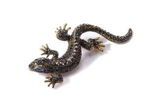 Detail of vintage lizard brooch with grey rhinestones and blue crystal eye on gold metal