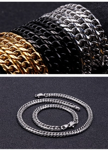 Close-up of gold, black and silver stainless steel Cuban link chains on dark fabric