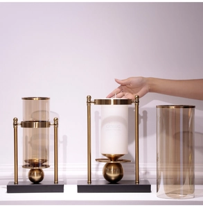Detail of luxury gold metal candle holders with tinted glass covers and black square base