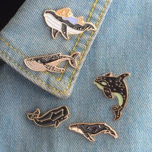 Set of five cosmic whale enamel pins pinned on blue denim collar for creative decoration
