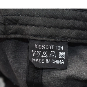 Detail of internal care label on a black 100% cotton baseball cap showing wash icons