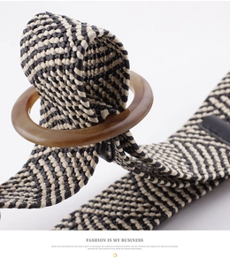 Detail of woven straw belt featuring black and white V-pattern and amber resin buckle