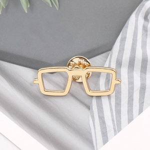 Macro shot of gold glasses brooch with polished metal finish and secure pin back