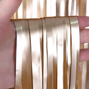 Close-up of hand holding matte golden foil fringe curtain for birthday party decor