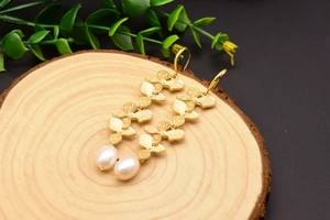 Close-up of vintage floral gold earrings with white teardrop pearls on wood