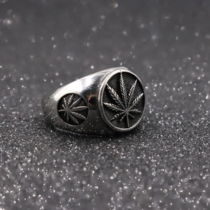 Detailed relief of a hemp leaf on a metallic ring against a black glitter background