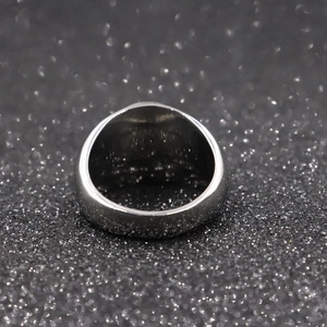 Close-up of the silver metal eagle wing ring back on a textured black background