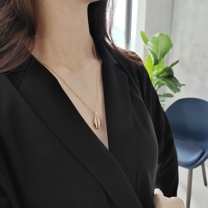 Elegant gold shell pendant necklace shown on model wearing black deep V-neck dress