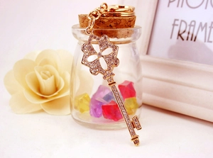 Close-up of sparkling rhinestone-studded golden four-leaf clover key charm on a keychain