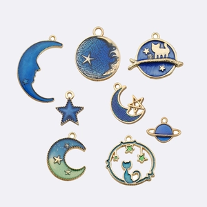 Flat lay of blue enamel celestial pendants including moons, stars and planet charms