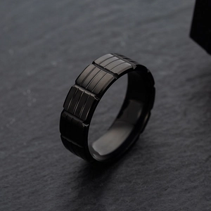Macro view of men's black stainless steel ring with industrial geometric texture