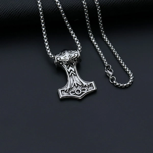 Macro shot of silver Thor's hammer pendant with engraved COD text on box chain