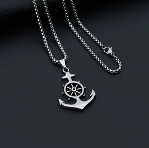 Macro shot of silver anchor and helm charms on box chain with antique metal finish