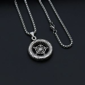 Close-up of silver steel necklace with round hollow star pendant on black background