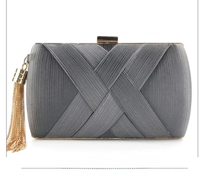 Detail of dark grey satin evening clutch with elegant gold tassel and metallic frame