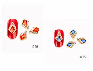 Makroaufnahme geometrischer Nagel-Charms mit roten und blauen Strasssteinen und Pavé-Rand