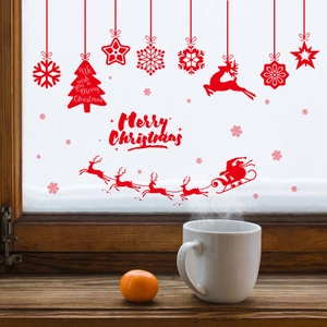Red Christmas window decals featuring reindeer, snowflakes and Santa on a snowy glass window