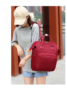 Outdoor shot of a red quilted nylon mommy backpack with spacious pockets for travel