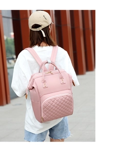 Pink quilted nylon diaper backpack with multi-pocket design shown on model outdoors