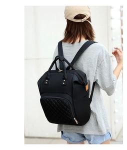 Detail of black nylon diaper backpack featuring quilted pockets and gold metal zippers