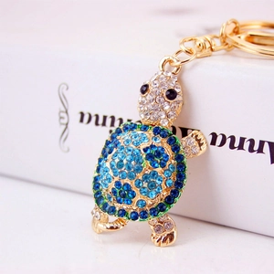 Golden turtle keychain with blue rhinestones and lobster clasp on white book