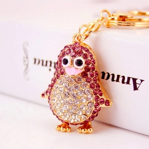 Sparkling cartoon penguin keychain with pink and white rhinestones on golden base