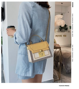 Fashionable beige crossbody bag with woven edges and gold handle worn by a model