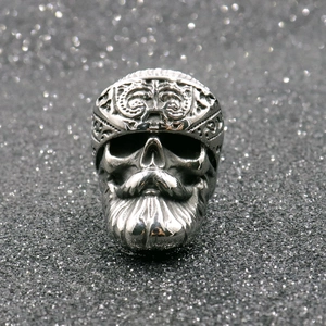 Anello teschio vintage in acciaio inossidabile con barba e fascia su sfondo grigio glitter
