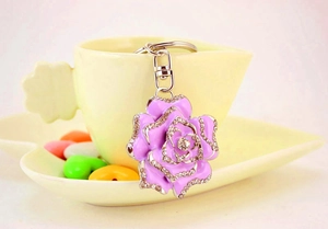 Detailed view of a purple rhinestone rose keychain hanging on a tea cup edge