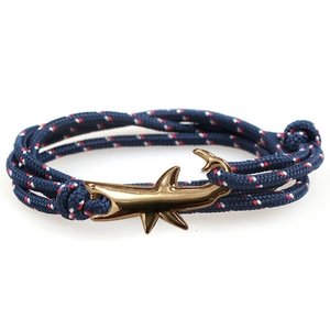 Shark anchor bracelet featuring navy blue braided cord and polished gold shark clasp