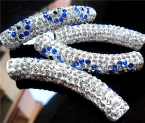 Macro shot of curved tube beads with inlaid blue and white rhinestones for jewelry making
