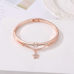 Detail eines roségoldenen Armreifs mit Sternanhänger und funkelnden Zirkoniasteinen