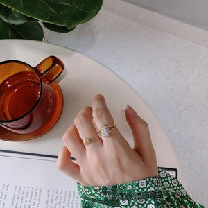 Close-up of gold pear-cut gemstone ring and V-shaped pave band set worn on hand