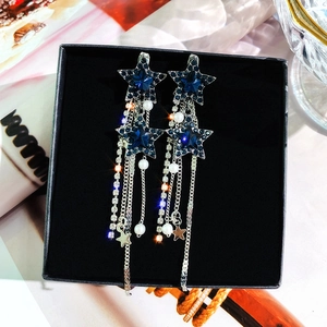 Detail of elegant star earrings with blue crystals and long pearl tassels in a black box