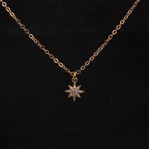 Elegant gold chain necklace with a star pendant set with clear crystals on black background