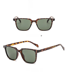 Detail of square tortoiseshell frame sunglasses with green lenses and metal rivets