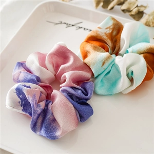 Detail of colorful tie-dye satin scrunchies in pink-purple and orange-blue on a white tray
