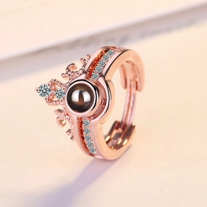 Rose gold crown ring with projection stone and decorative diamond-like stones on a beige background