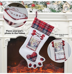 Dog paw Christmas stocking with red buffalo plaid trim and photo frame on a fireplace